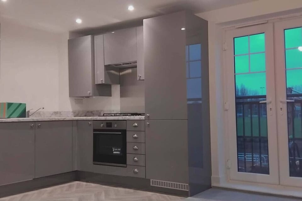Modern grey kitchen area with built-in oven beside glazed doors