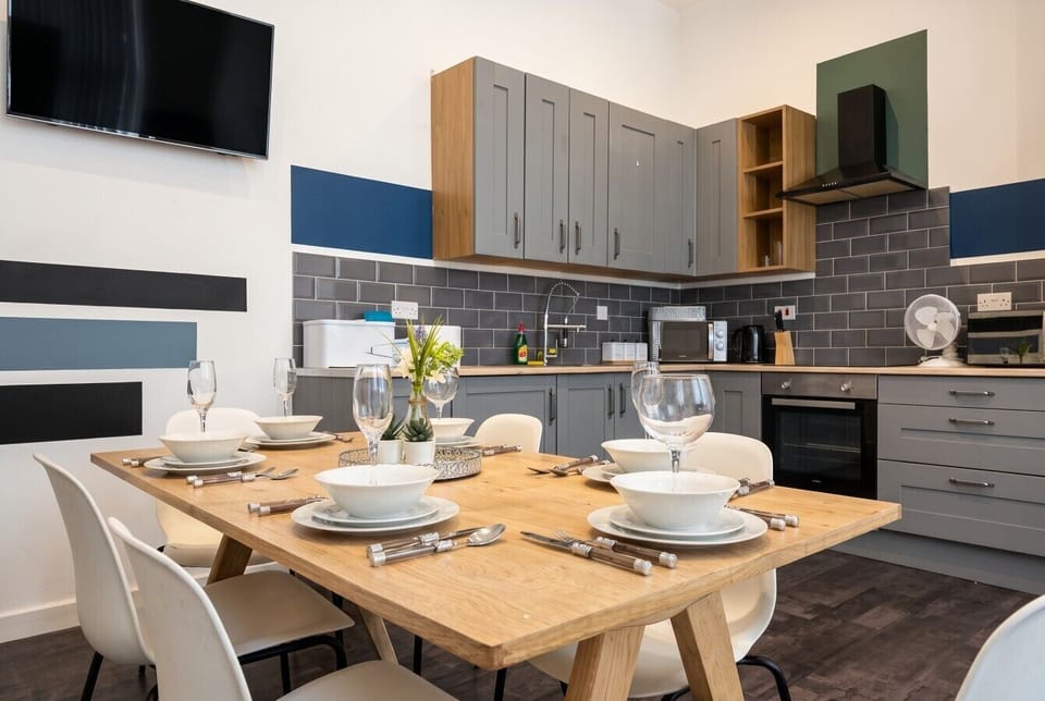 Gather friends around the dining table beside a fully fitted kitchen with TV nearby.