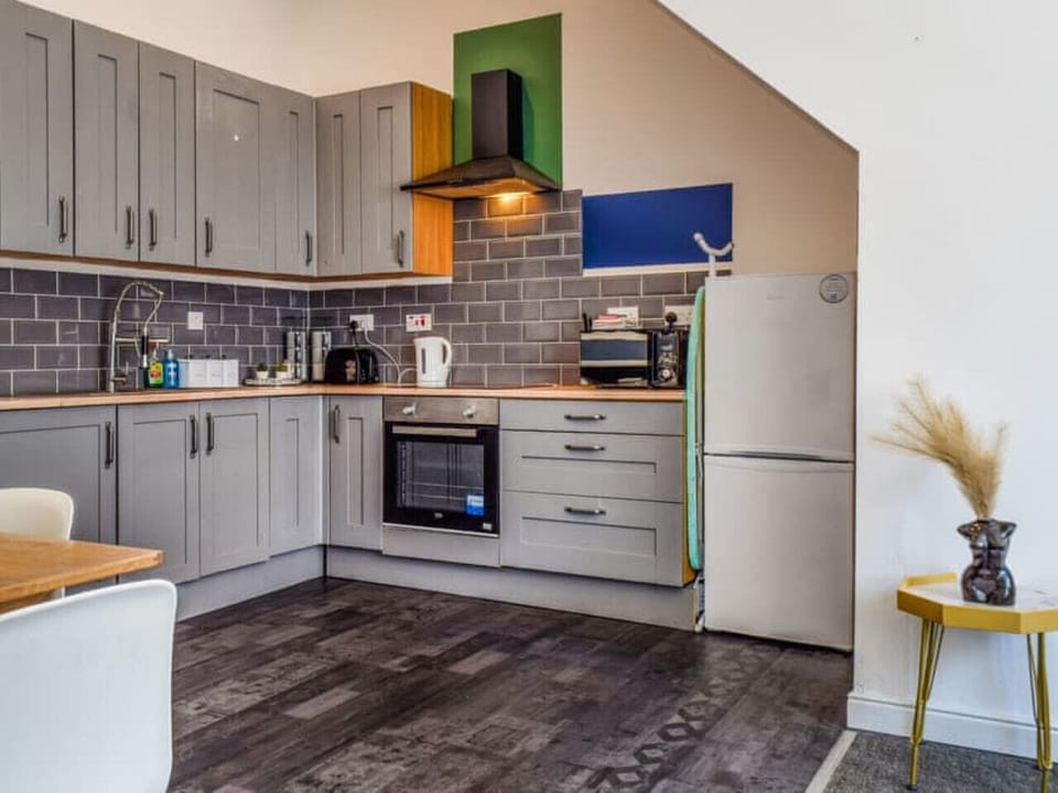 Prepare meals in the fitted kitchen with oven, hob, and full-height fridge.