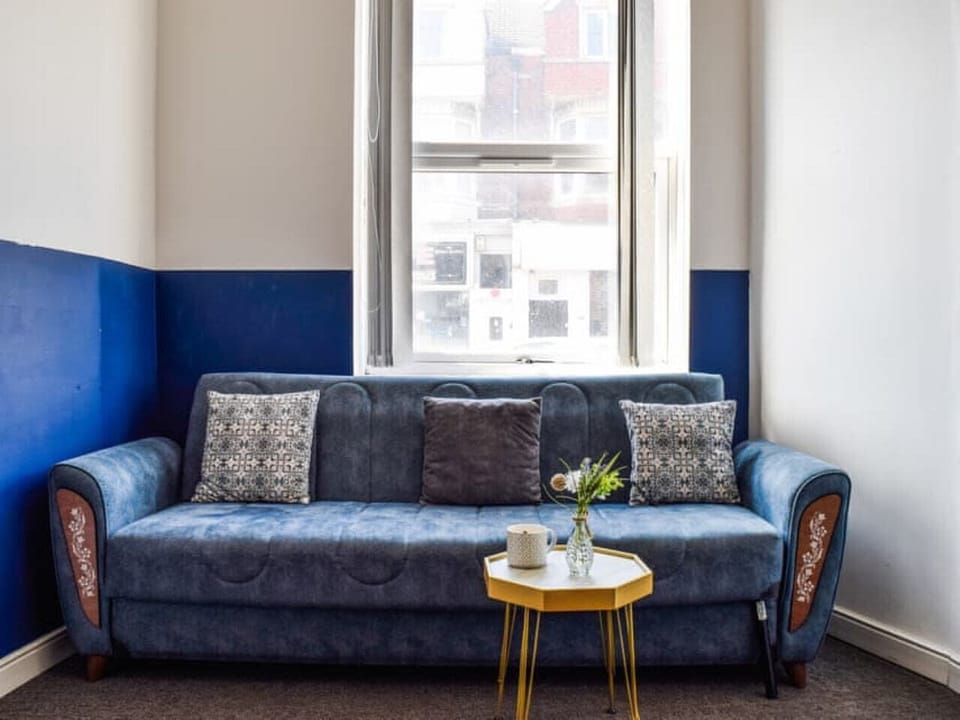 A sofa is positioned beneath a bright window in the living area.