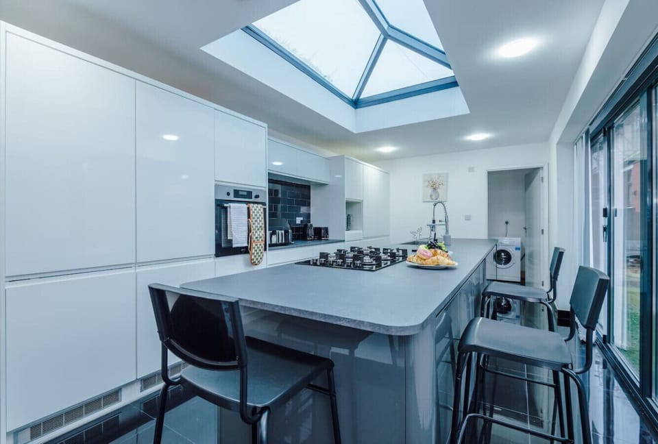Kitchen island with bar stools beside glazed doors looking onto the garden.