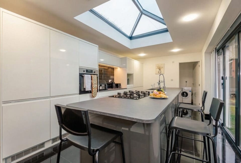 Skylit designer kitchen with island hob and bar seating for a brilliant group breakfast.