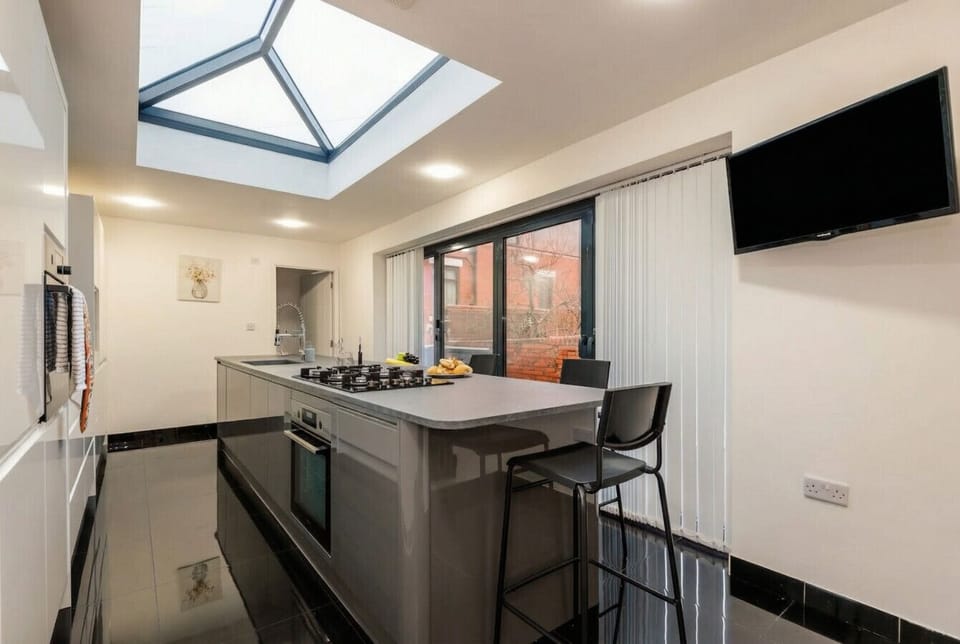 Sleek kitchen extension with lantern skylight, island seating, and bifold garden doors.