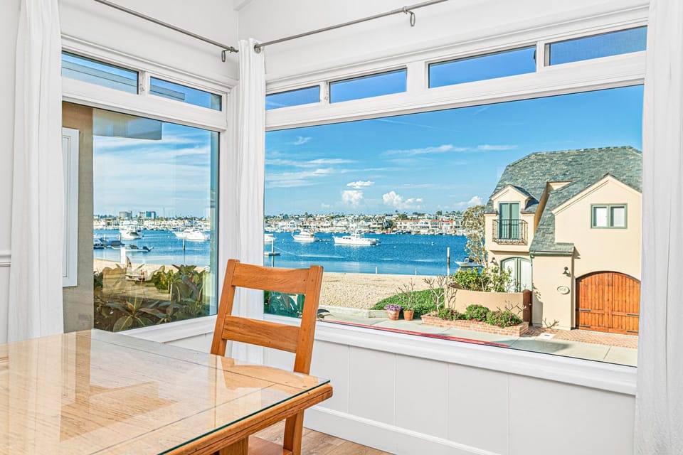 Expansive bay-view windows create a serene backdrop, where passing boats add to the rhythm of relaxed coastal living
                