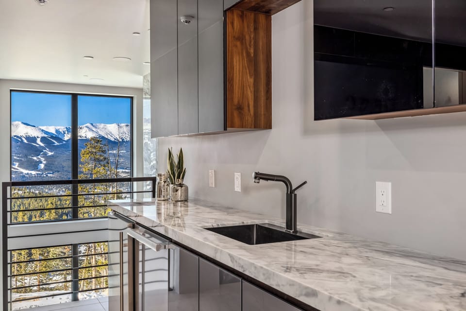 Savor your morning coffee in this sleek kitchen while taking in breathtaking mountain views through floor-to-ceiling windows.