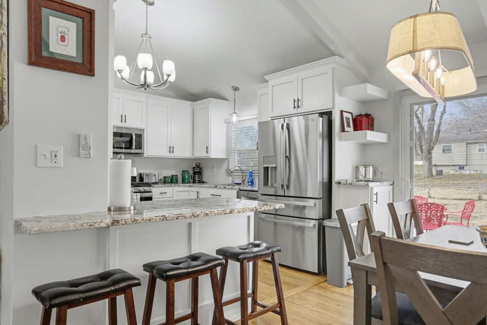 Updated kitchen featuring stainless steel appliances, white cabinetry, granite countertops, and bar seating for casual meals or morning coffee before heading out for the day.