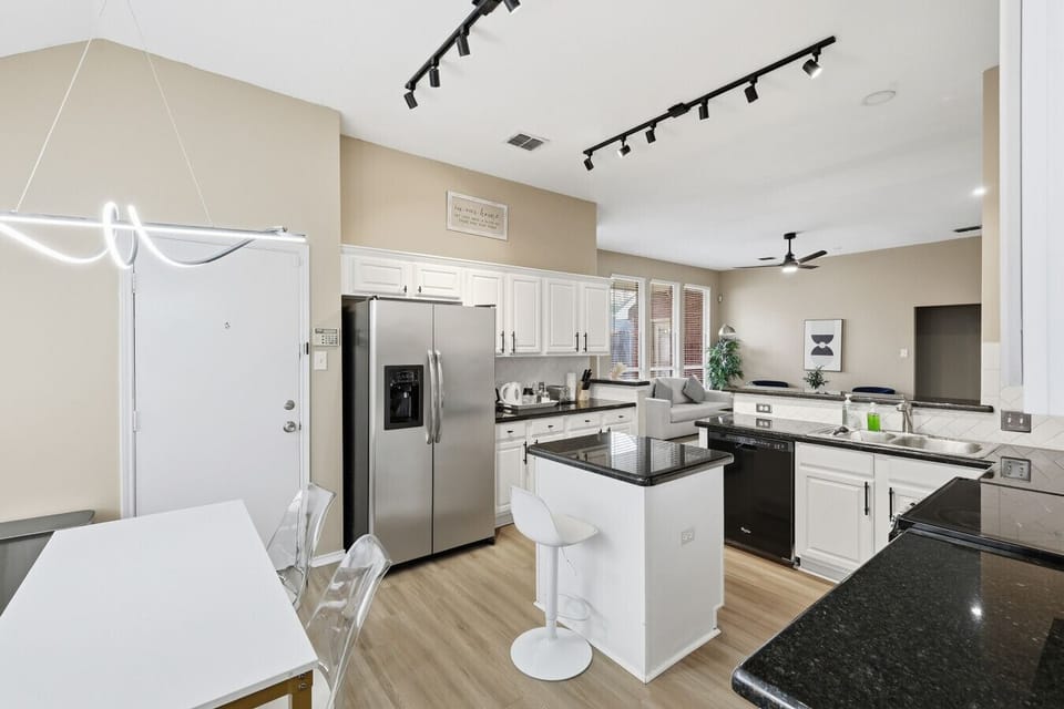 Stunning open-concept layout featuring a fully equipped kitchen with stainless steel appliances, breakfast bar