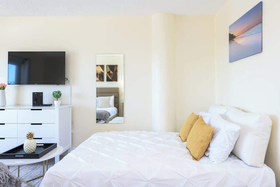 Modern comfort meets coastal flair—relax in this bright bedroom with bold accents and entertainment.