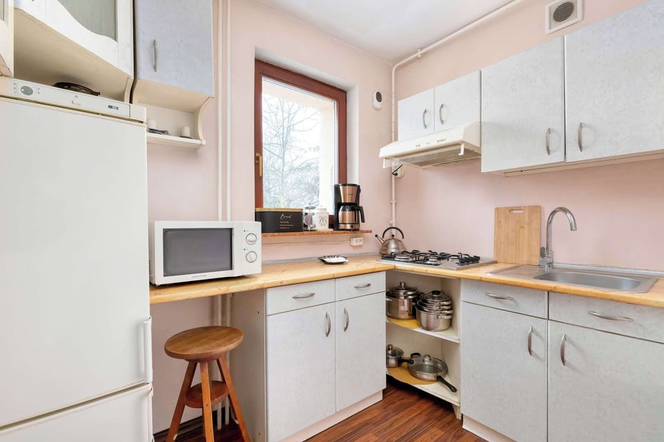 The compact kitchen is equipped with white cabinetry, a microwave, and a gas stovetop for convenient meal preparation. A wooden countertop and a small window bring a bright, homey feel to the cooking area.