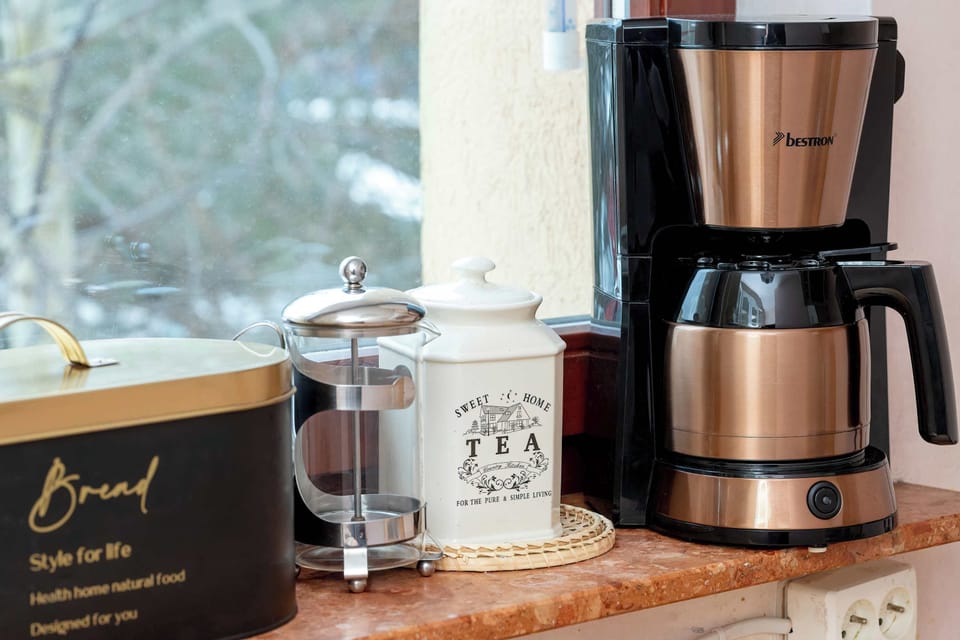 A dedicated coffee station features a modern French press and a drip coffee maker alongside decorative canisters. This setup is perfect for guests to enjoy a fresh morning brew.