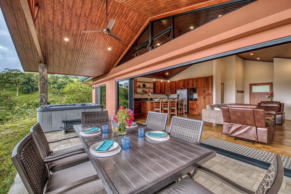 The covered patio enjoys a beautiful dinner table and hot tub.
