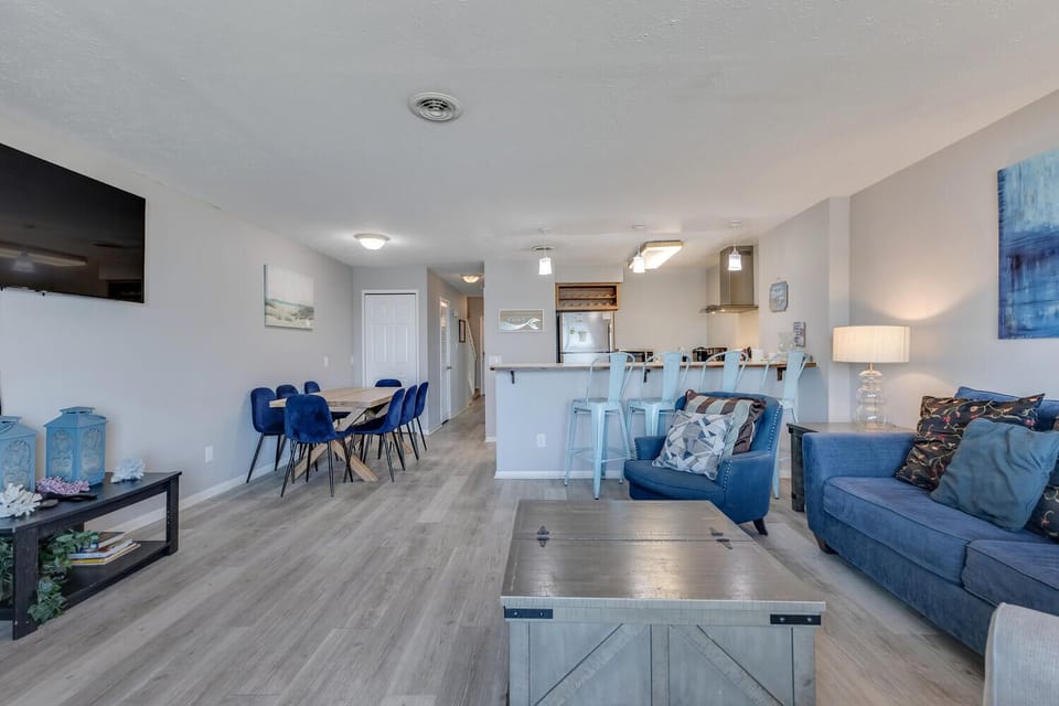 Relax in your spacious open-concept living area featuring coastal blue accents and modern comforts that perfectly blend style with home-away-from-home convenience.