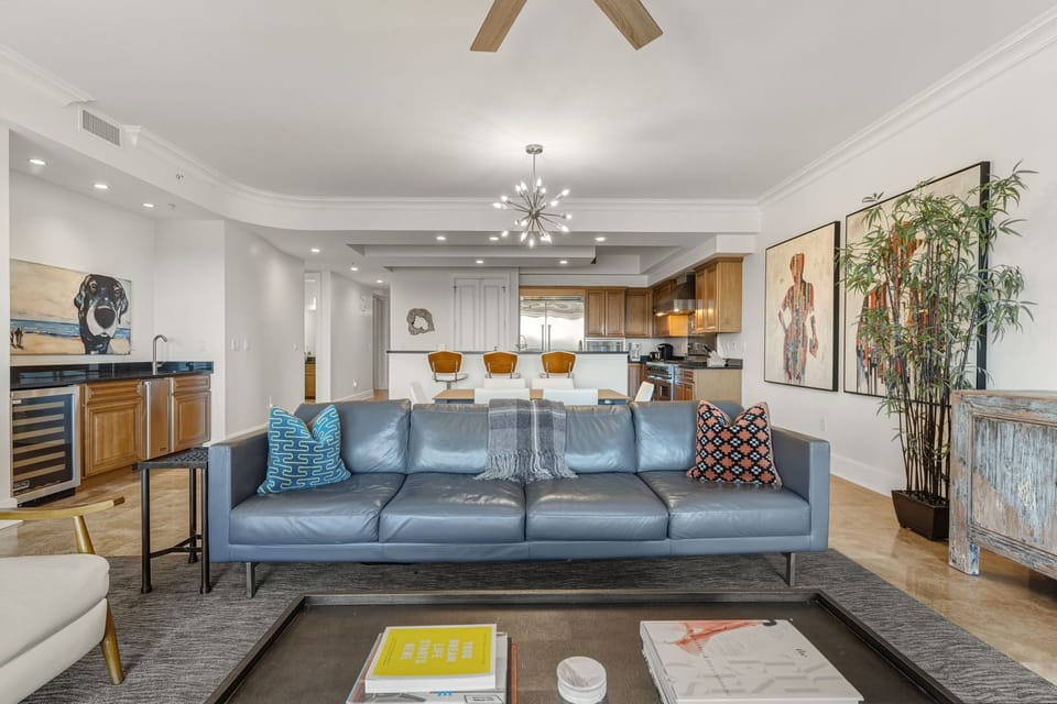 Sink into this stylish blue leather sofa and enjoy the open-concept living with modern kitchen, artistic touches, and warm wood accents throughout.
