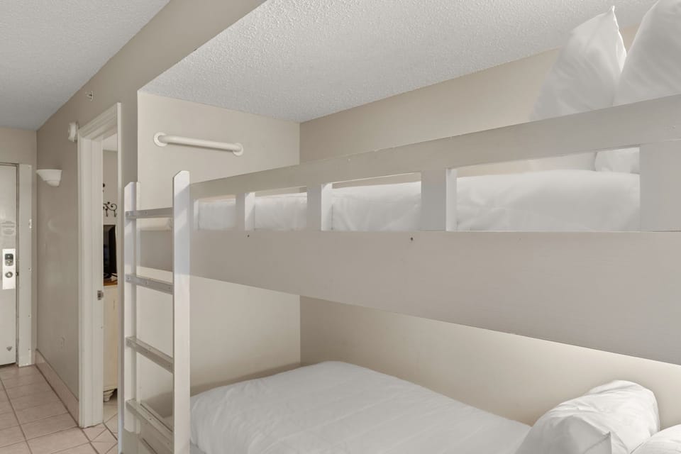 Cozy bunk bed space features crisp white linens and modern built-in design, perfect for restful nights.