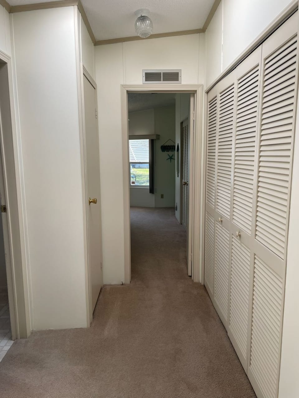Hallway to secondary bedroom with large closet and linen closet.