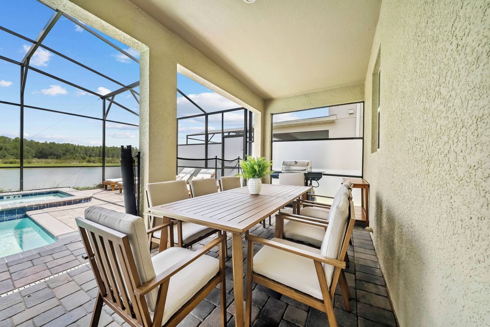 Enjoy a delightful meal in our charming patio dining area, featuring a stylish wooden table and comfortable seating. Large screens let in fresh air while you take in views of the inviting pool and serene surroundings.