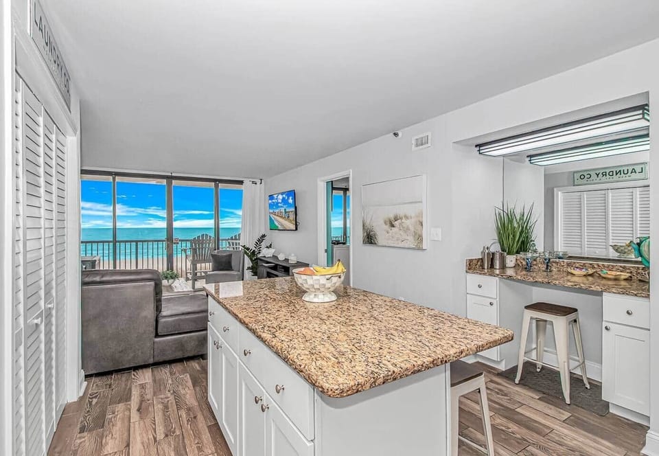 Open kitchen with island seating & ocean views beyond.