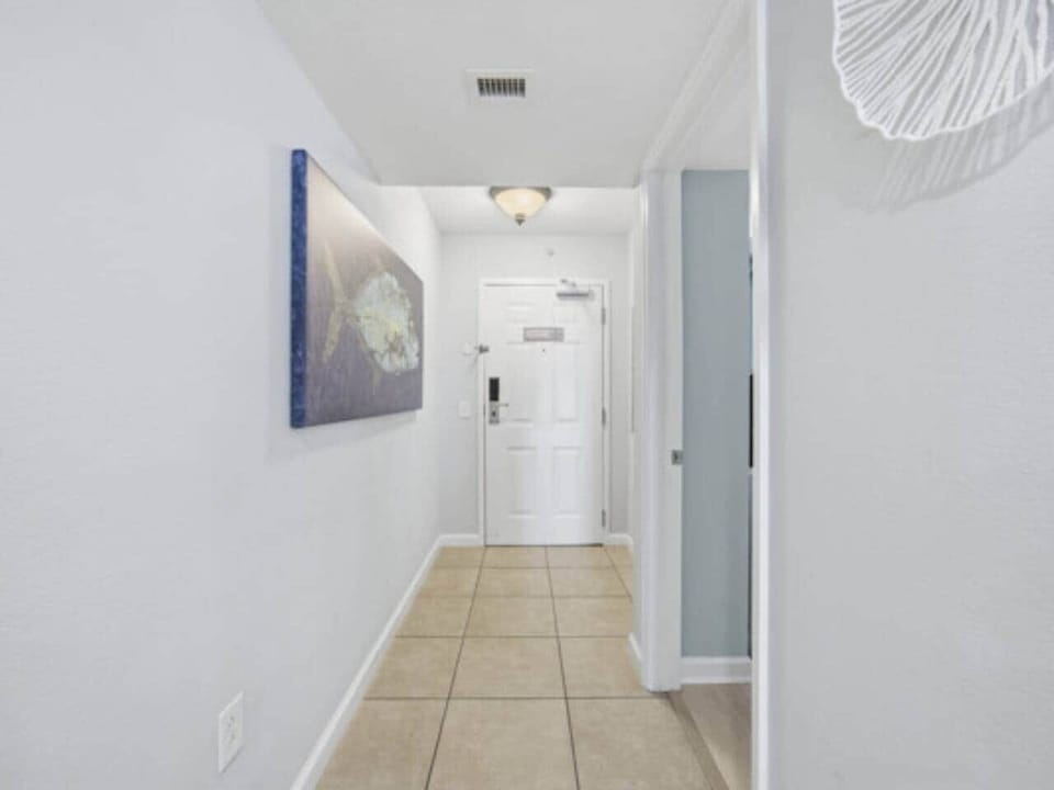 Spacious hallway leading into the unit with coastal artwork