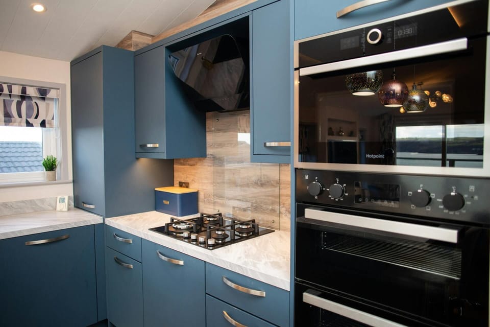 Modern kitchen with blue cupboards, extractor hood and tiled splashback