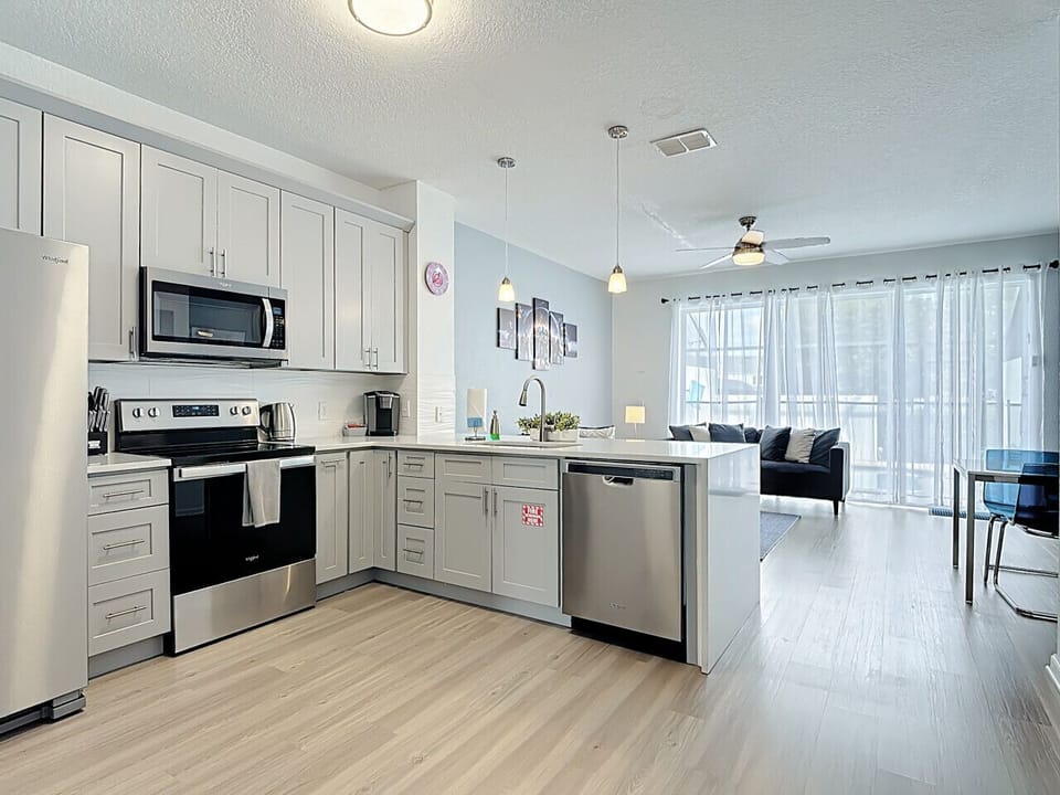 Bright, modern kitchen with stainless steel appliances, white cabinetry, and an open layout flowing into the living area.