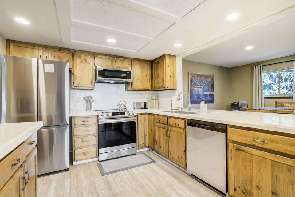 The kitchen is equipped with a modern glass-top stove and a large refrigerator to accommodate your grocery needs. A dishwasher is integrated into the cabinetry for easy cleanup after enjoying a home-cooked meal in the unit.