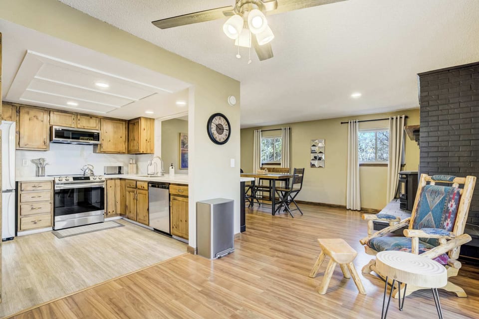 This sun-drenched kitchen features warm knotty pine cabinetry and sleek professional-grade appliances. The open layout is designed for easy meal prep with a clean white backsplash and expansive countertops for your use.