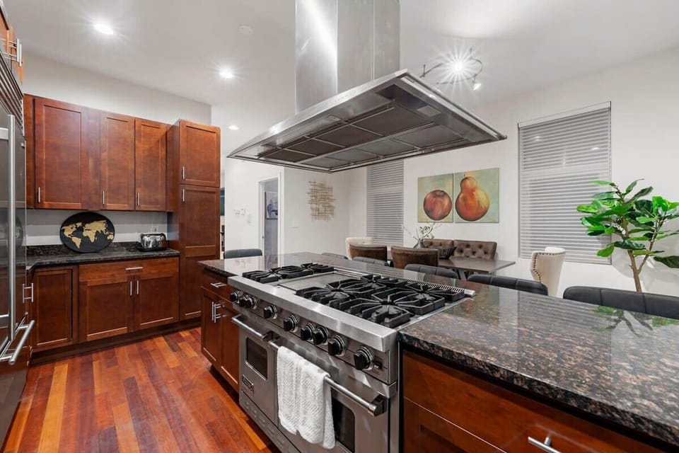 Chef-friendly kitchen w/ a gas range, sleek hood, dark counters, & plenty of space to prep meals.