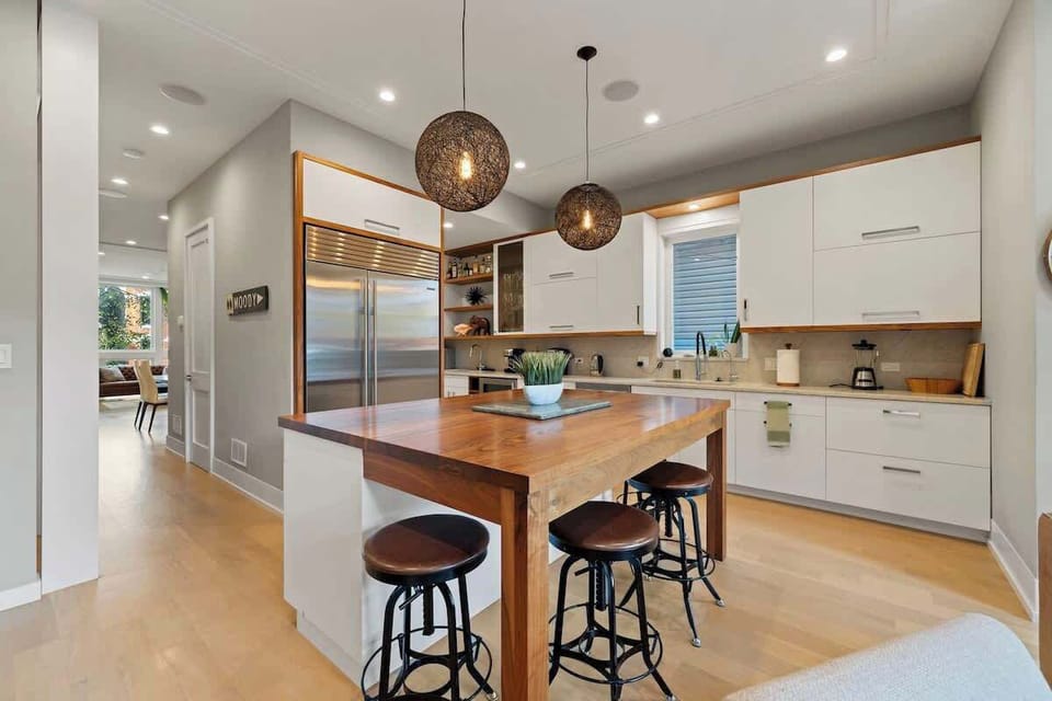 Gather around the spacious kitchen island w/ bar seating, warm wood accents, & statement lighting.