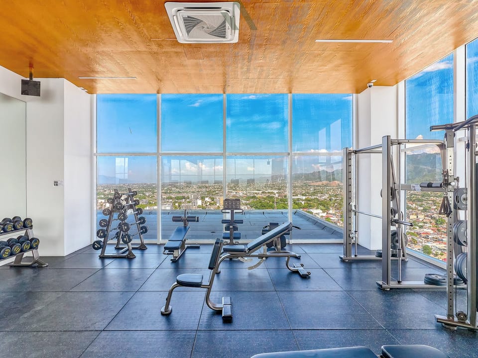 Train in a spacious fitness center featuring free weights, strength machines, and cardio equipment with stunning city and ocean views