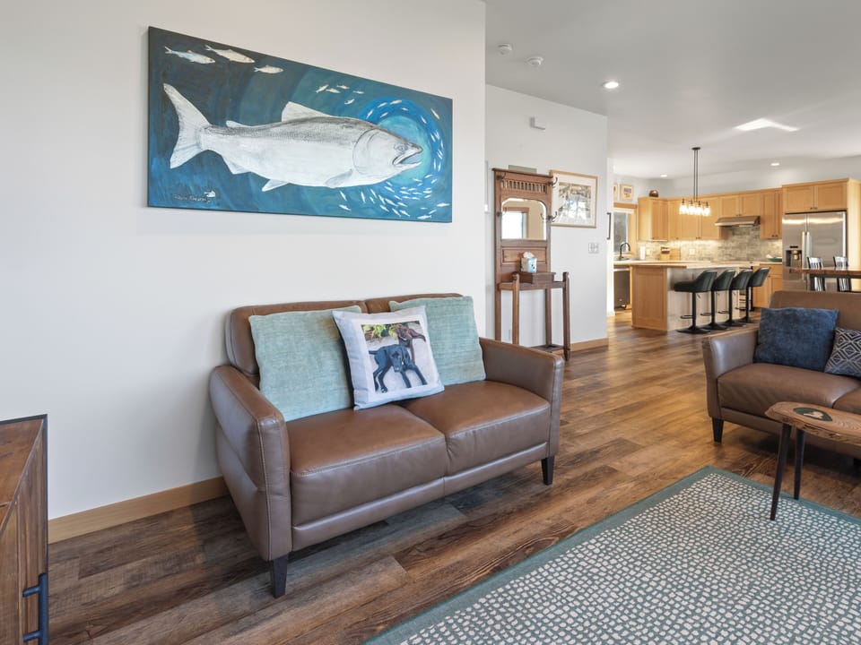 Relax in your stylish living space with rich leather seating, nautical artwork, and an open kitchen perfect for preparing meals together.