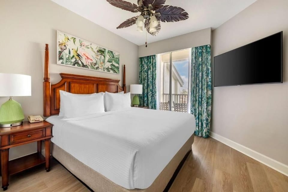 Unwind in a sunlit bedroom with balcony views and TV.