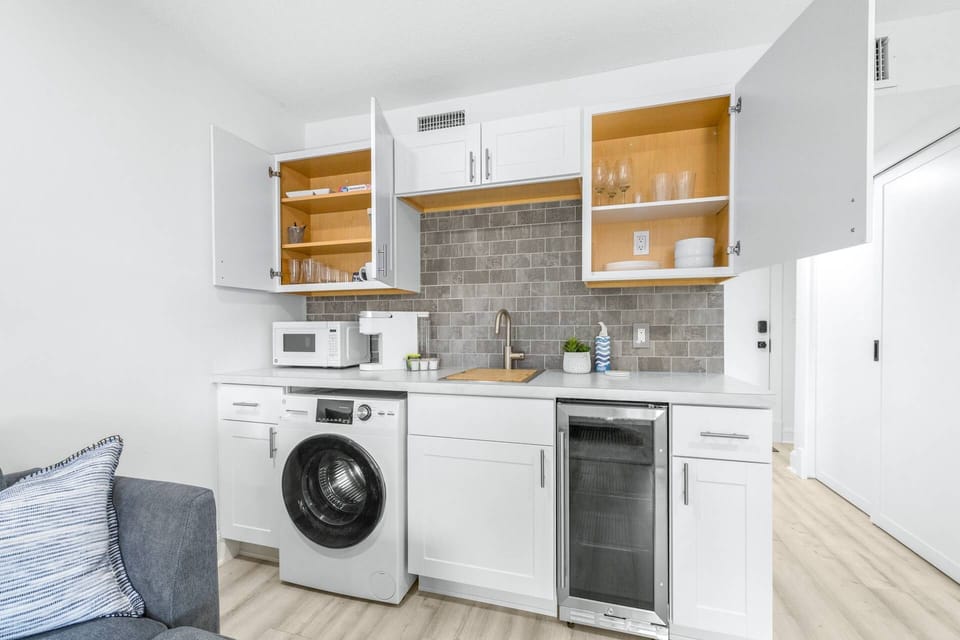 Modern kitchenette with stocked with Coffee, small fridge, microwave, and all-in-one washer/dryer in the connecting Studio.
