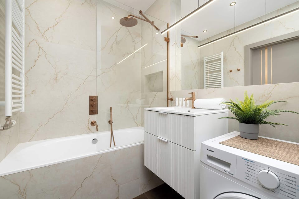 This wide angle captures the clean lines and bright aesthetic of the bathroom. Large mirrors and recessed lighting create a spacious, spa-like feel.