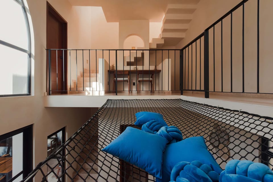 Rooftop terrace seating nook with decorative tiling, hammock, and open-sky Tulum views.