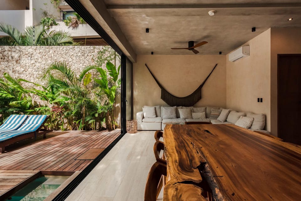 Outdoor lounge with macrame hammock, striped sunloungers, and lush tropical garden setting.