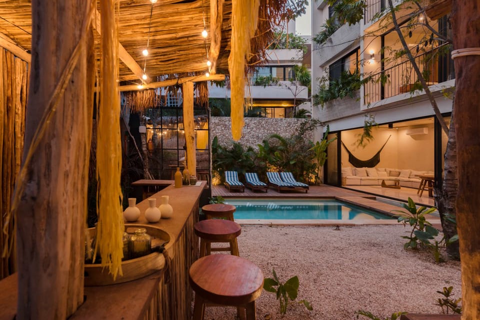 Tiki bar and outdoor entertaining area with pool backdrop and lush tropical garden.