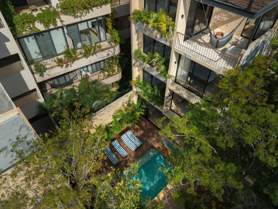 Aerial view of villa complex immersed in lush Tulum jungle canopy.