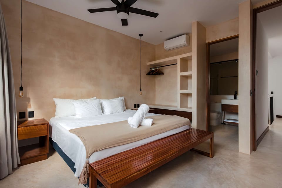 Bedroom with warm dark wood built-ins, white bedding, and wall sconce lighting.