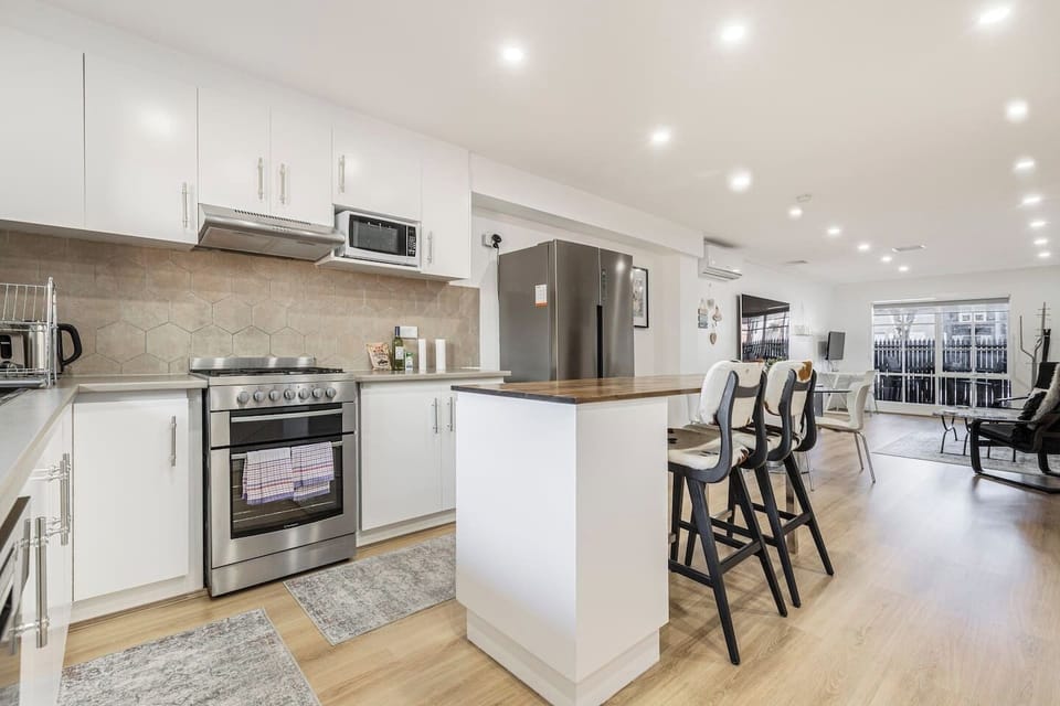 Chat over drinks at the breakfast bar as dinner sizzles on the gas cooktop in the modern kitchen.