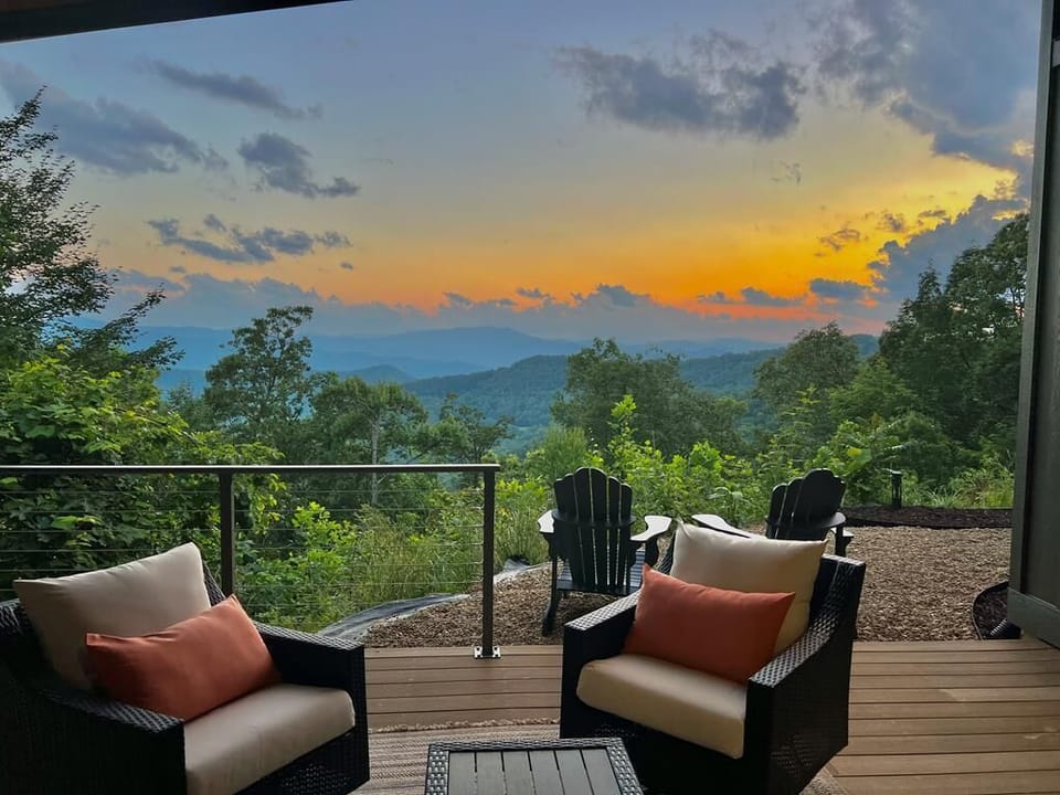 Breathtaking sunset view from the private deck of a luxury Bryson City cabin featuring modern glass railings and mountain vistas.