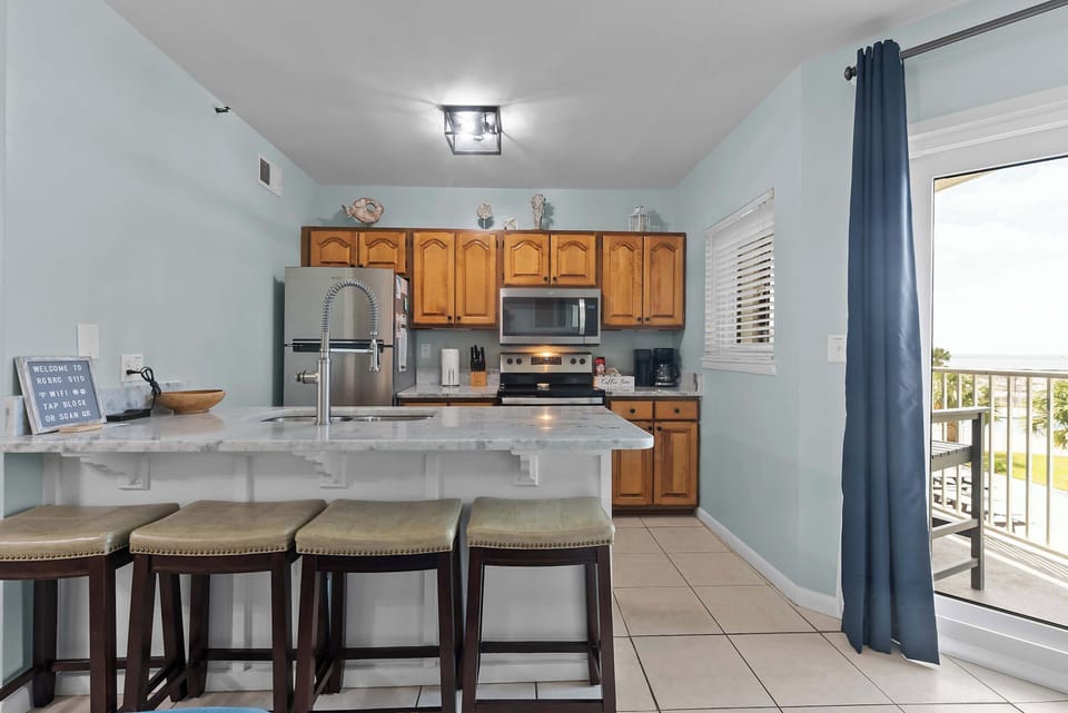 Open concept layout with kitchen, bar seating, and balcony doors