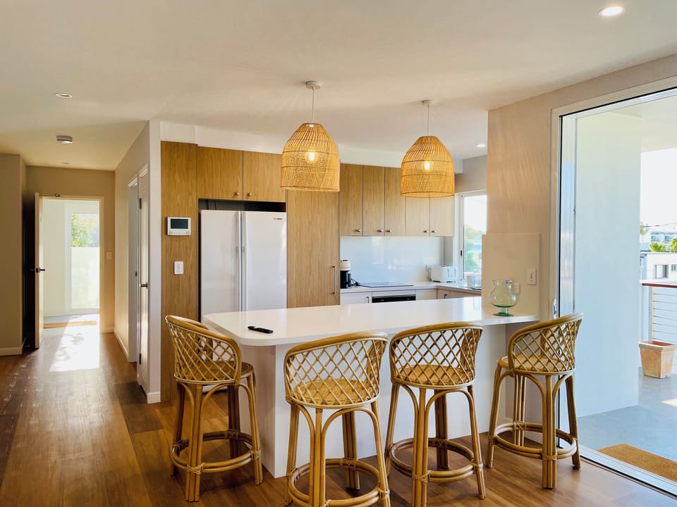 Large kitchen with 4 cane bar stools and pendant lights above