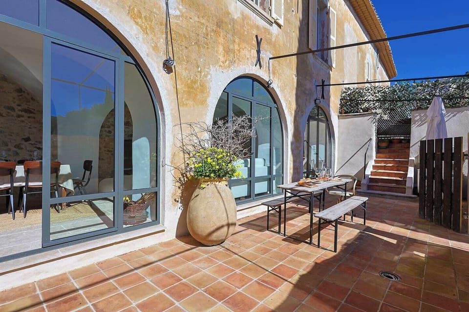A sun-drenched terracotta terrace framed by historic arches — the heart of La Maison LONG, where indoor and outdoor living blend effortlessly.
