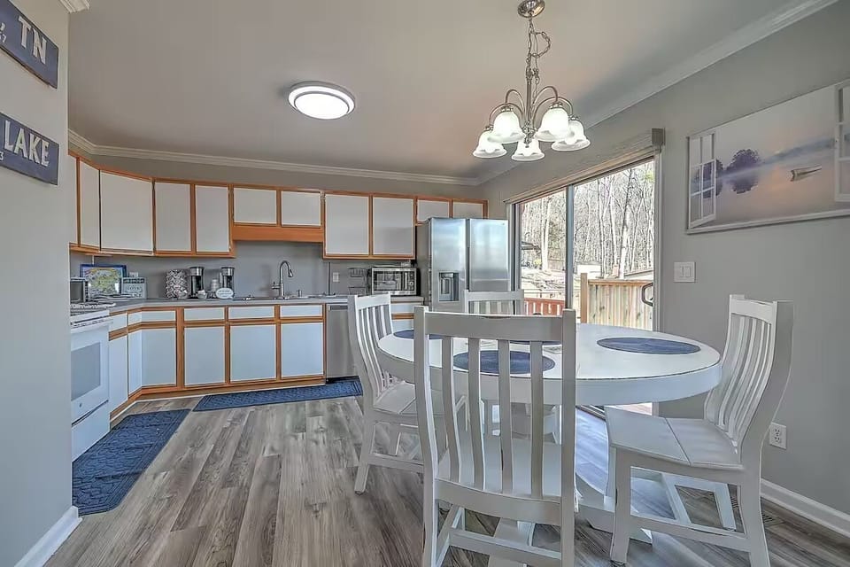 Spacious dining area connected to the kitchen, overlooking the outdoors through glass doors.