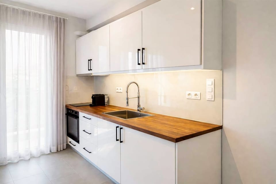 Modern kitchen with stovetop, oven, a kettle, a coffee machine, panini press and plenty of workspace. Fully equipped for preparing breakfasts, snacks, or full meals during your stay
