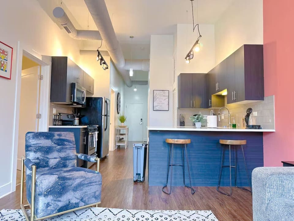 An open kitchen and living area with a bold accent wall, sleek dark cabinets, and cozy seating.