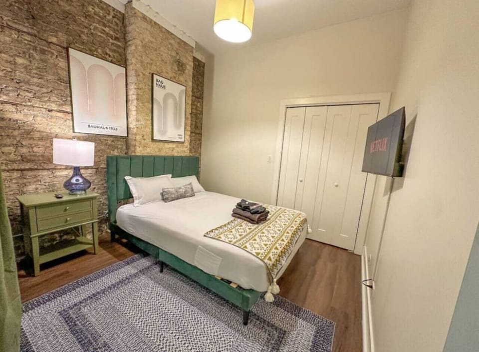 Stylish bedroom with exposed brick and comfy bed.