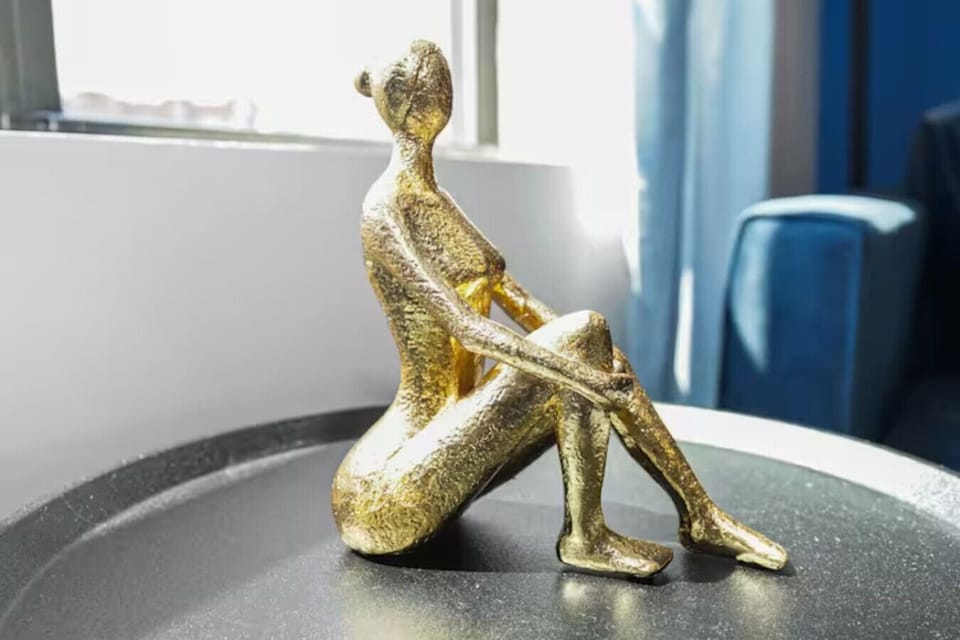 A small, golden, abstract sculpture of a seated figure adds artistic charm to the table.