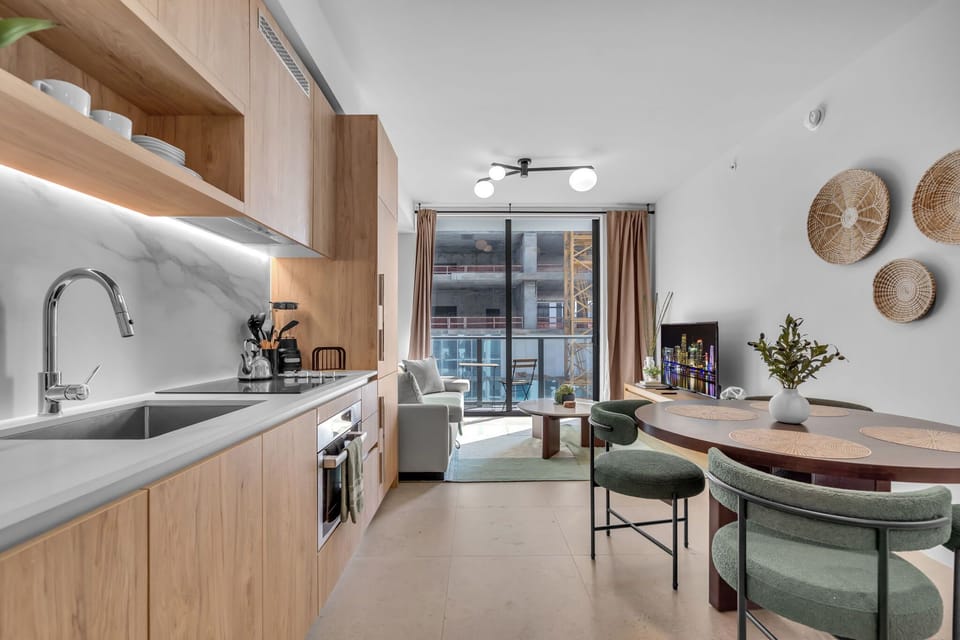 Sleek & modern fully equipped kitchen featuring gorgeous wood cabinetry and stainless appliances. Enjoy meals at the stylish dining table in this bright, open-concept space that flows effortlessly right out to the balcony!
