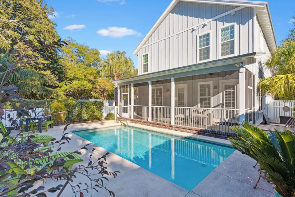 Beautiful coastal property with private swimming pool surrounded by tropical landscaping and covered front porch.